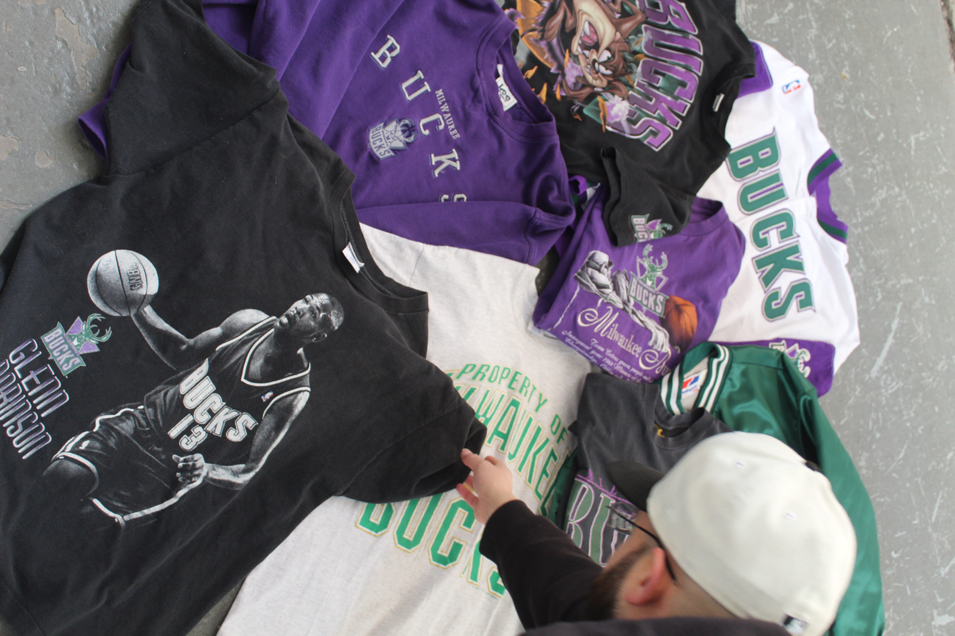 Vintage Milwaukee Bucks tees and jackets laid out on pavement while being sorted